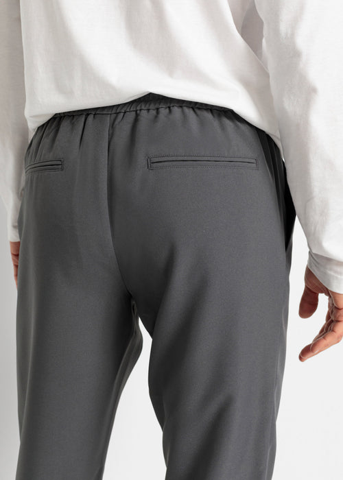 Ozke hlače za moško obleko z vpeljano elastiko okrog in okrog v spodaj zoženem kroju